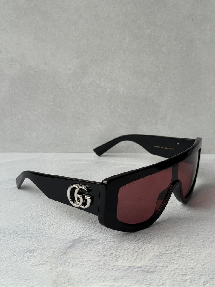 Black shield sunglasses with burgundy lenses and GG logo detail on temple