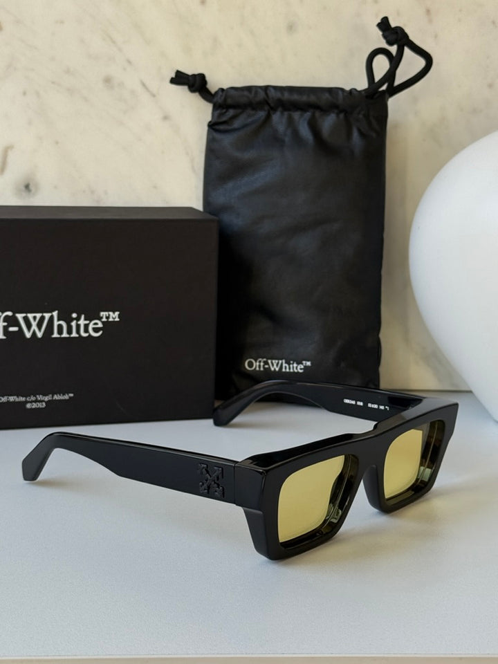 Black sunglasses with yellow lenses, side view with box and pouch