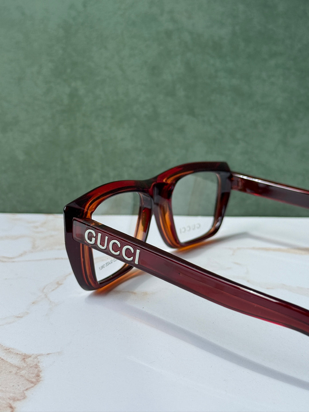 Dark red-brown Gucci eyeglass frames with logo on temple, angled view