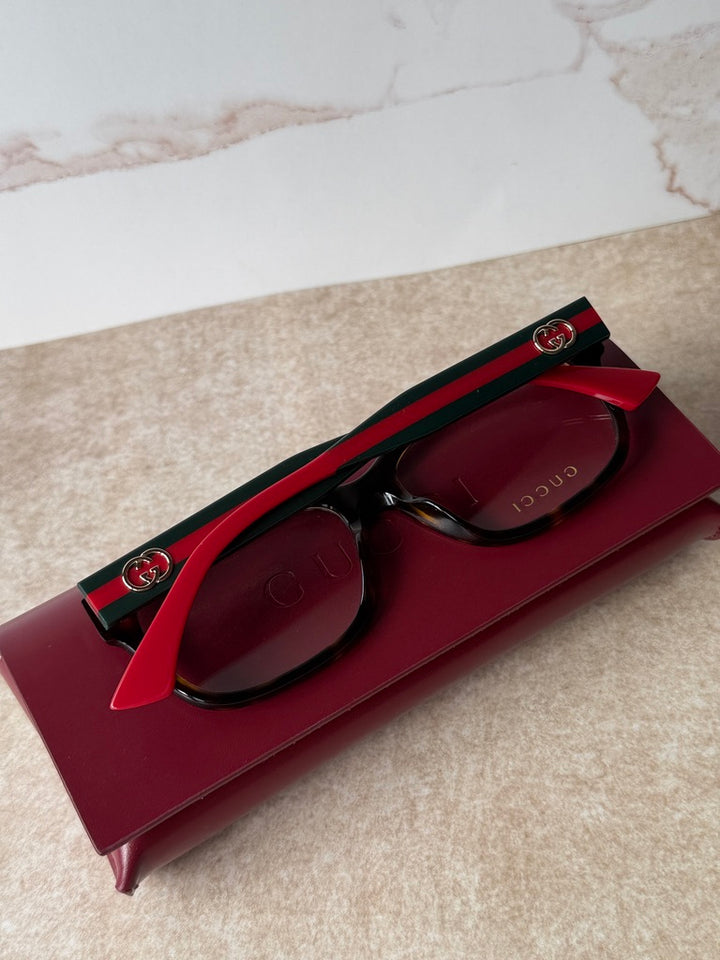 Black/red eyeglass frames with green stripe temple and Gucci logo