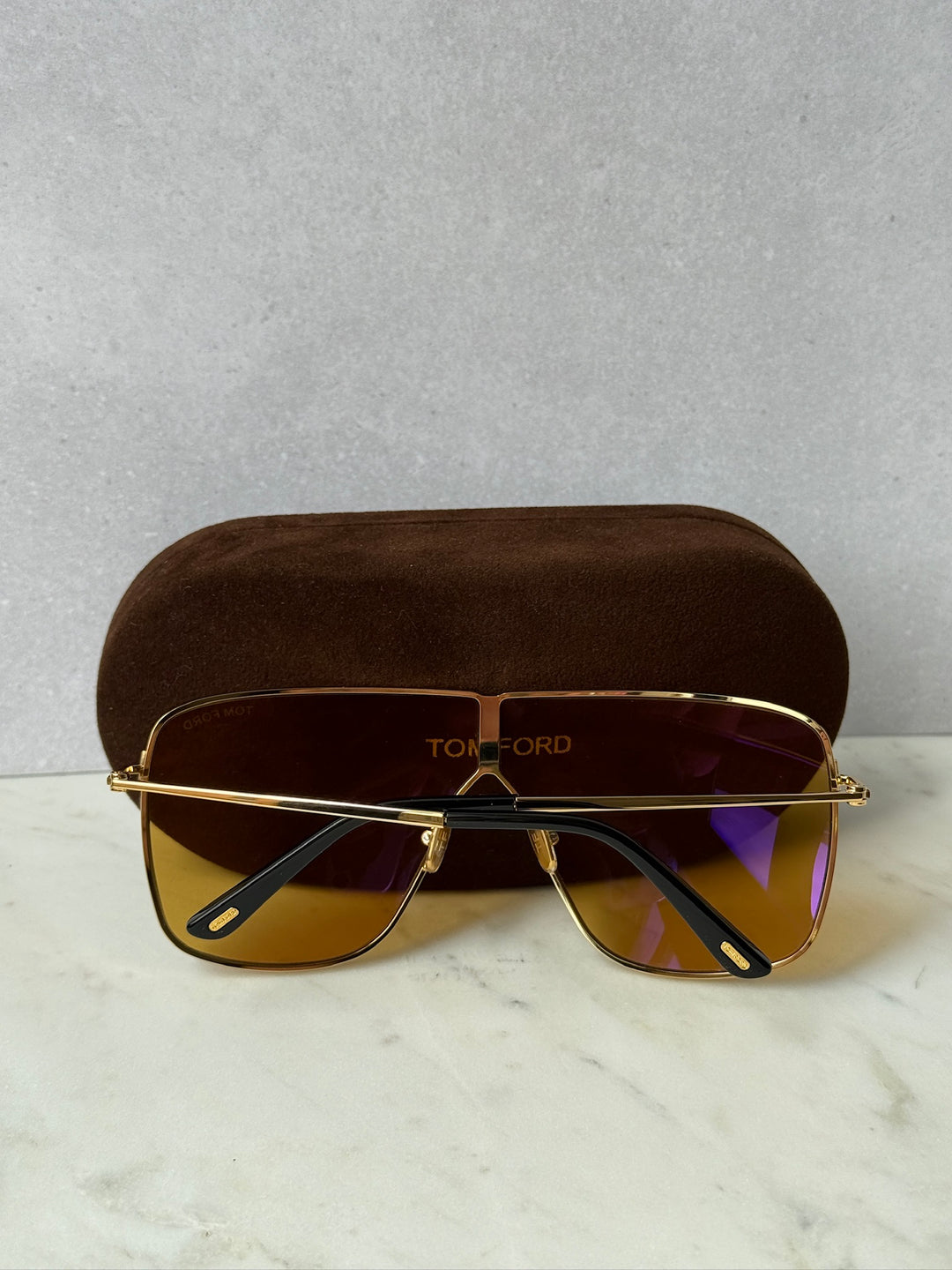 Gold square aviator sunglasses with gradient dark lenses, front view with brown case