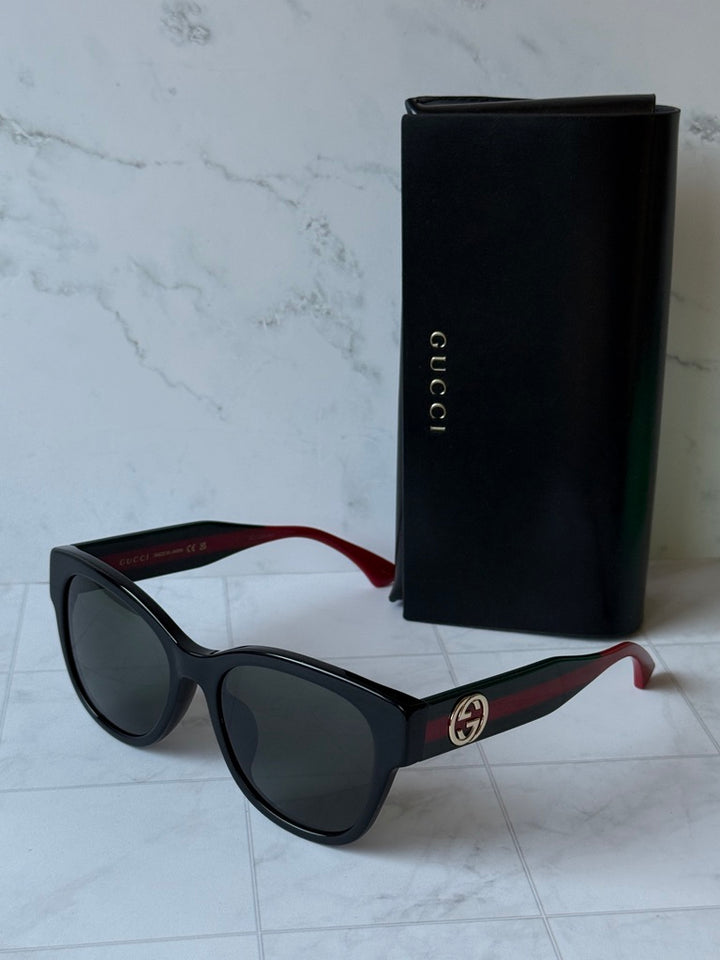 Gucci cat-eye style sunglasses, black frames, dark lenses, red-green temple stripes