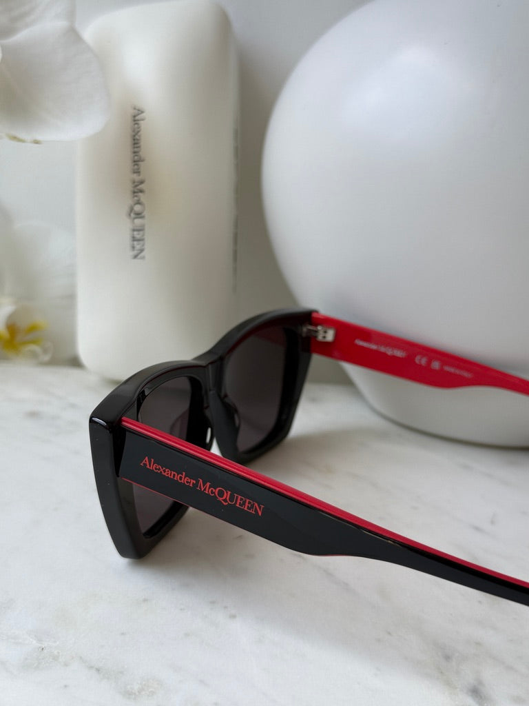 Black cat-eye sunglasses close-up with red temple bar and dark lenses