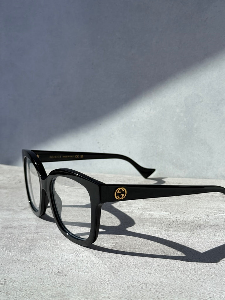 Black square eyeglass frames, side view with temple logo and angled arms