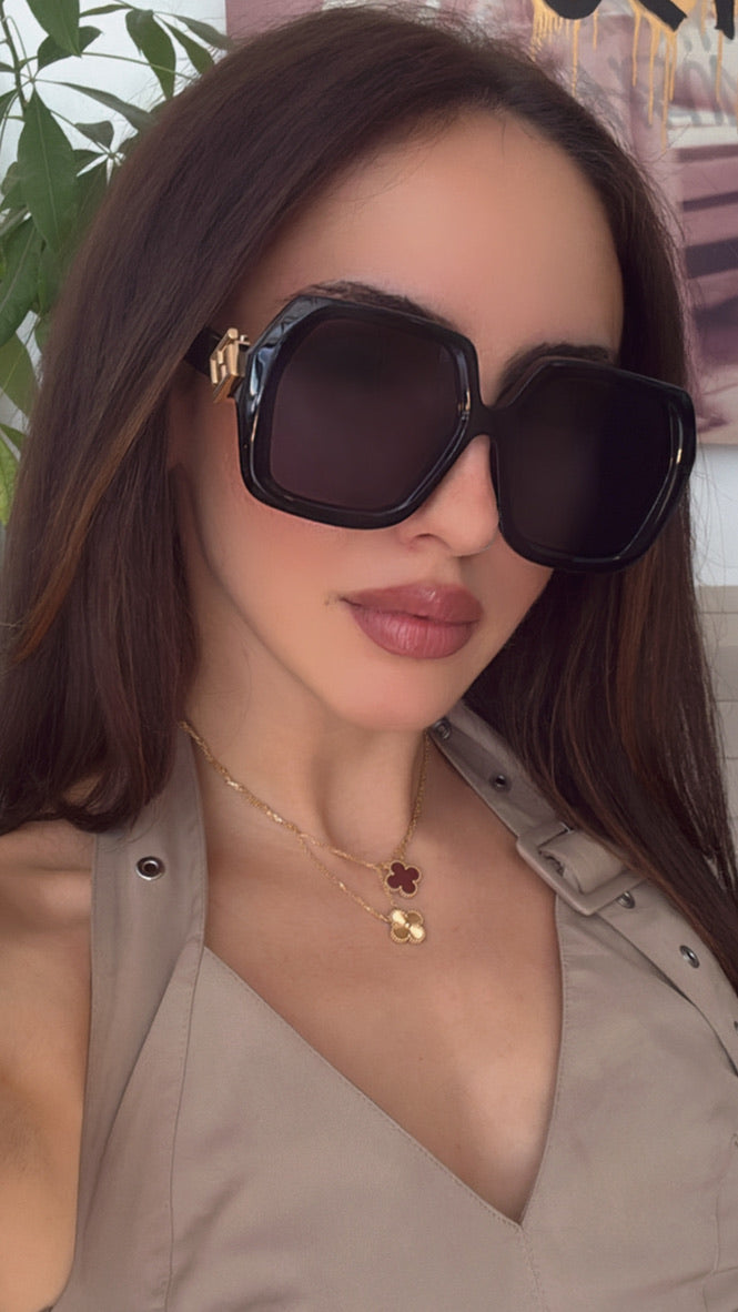 Woman wearing black square Fendi sunglasses with dark lenses and gold logo bridge