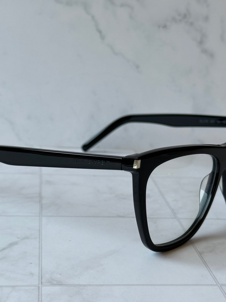 Black eyeglass frame corner with clear lens and metal hinge detail