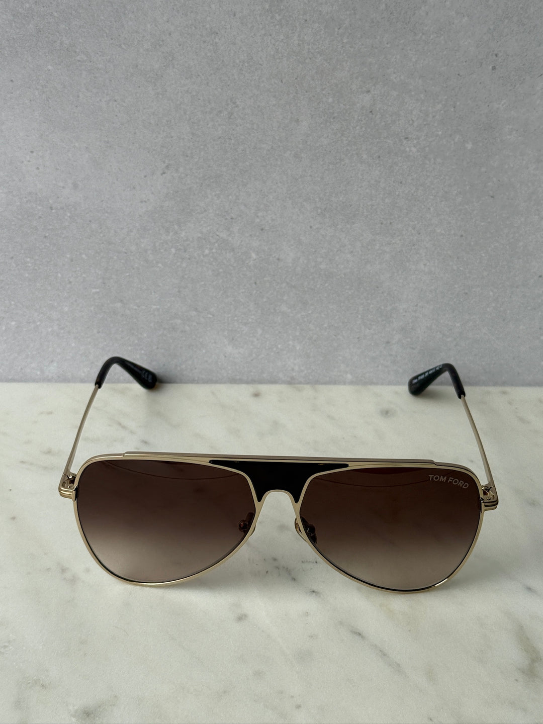 Aviator-style sunglasses with rose gold frame, dark lenses, and black temple tips