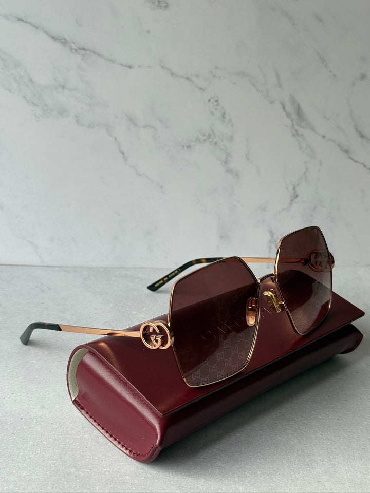 Oversized rose gold metal sunglasses with dark square lenses and logo hardware detail