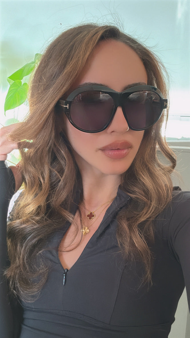 Woman wearing black cat-eye sunglasses with purple-tinted lenses