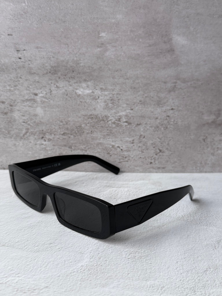 Prada black rectangular sunglasses with dark lenses, side view.