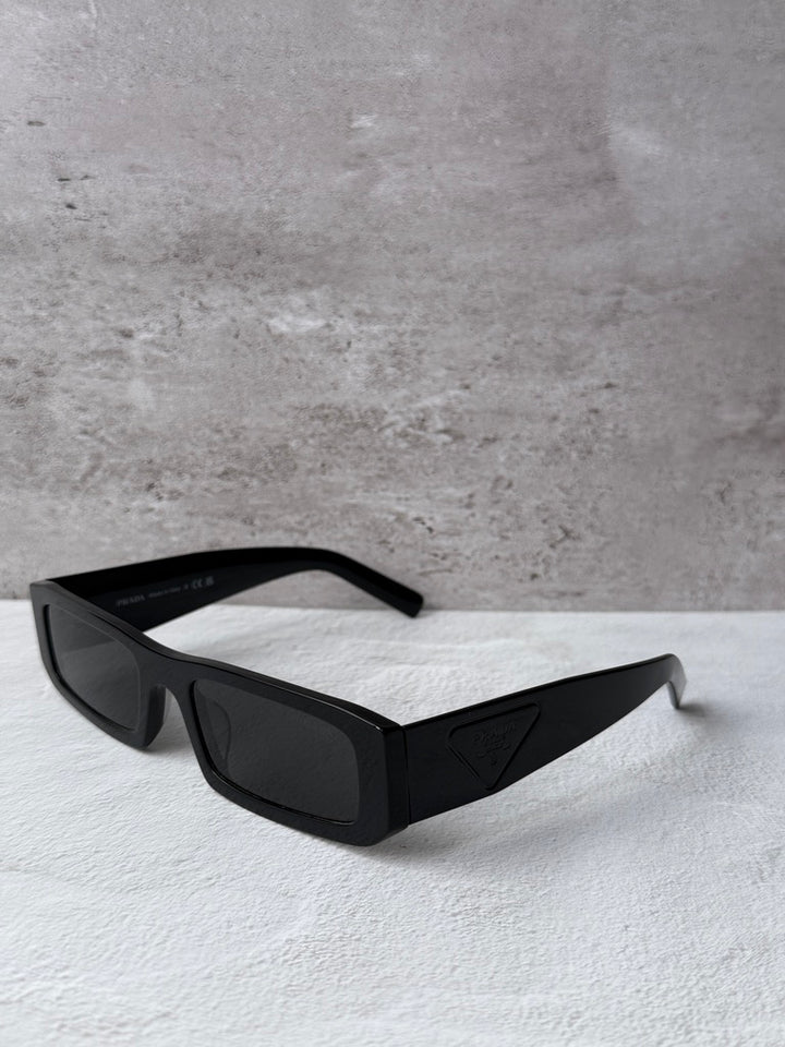 Prada black rectangular sunglasses with dark lenses, side view.