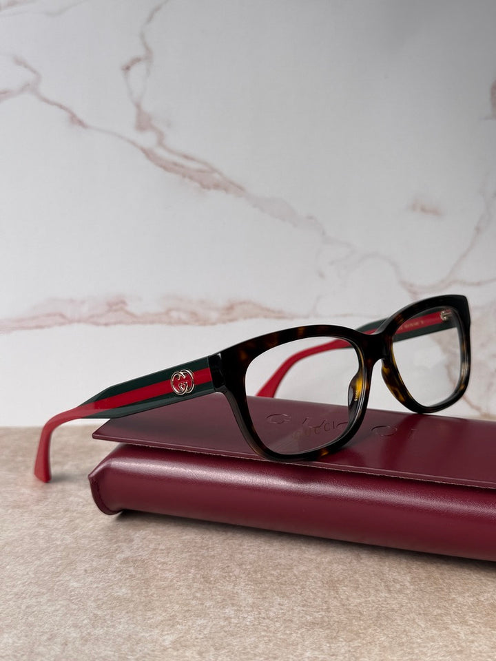 Dark tortoise eyeglass frames with red temples and green stripe detail