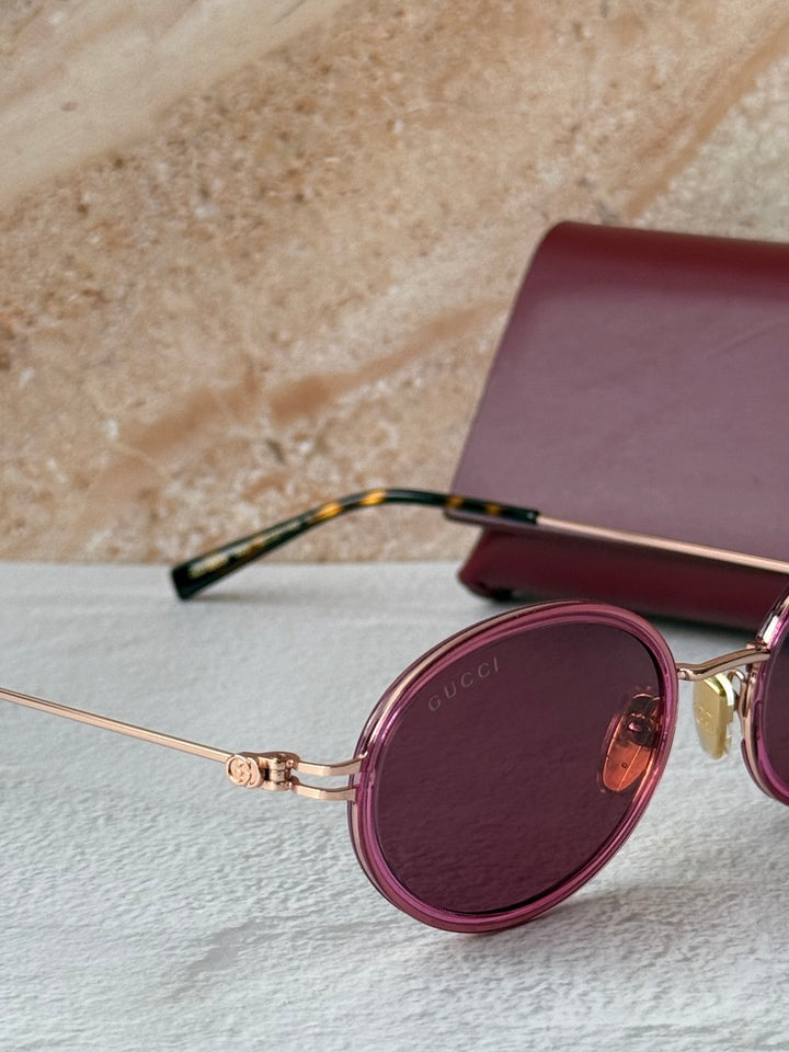 Gucci oval pink sunglasses close-up with dark lens and gold detail