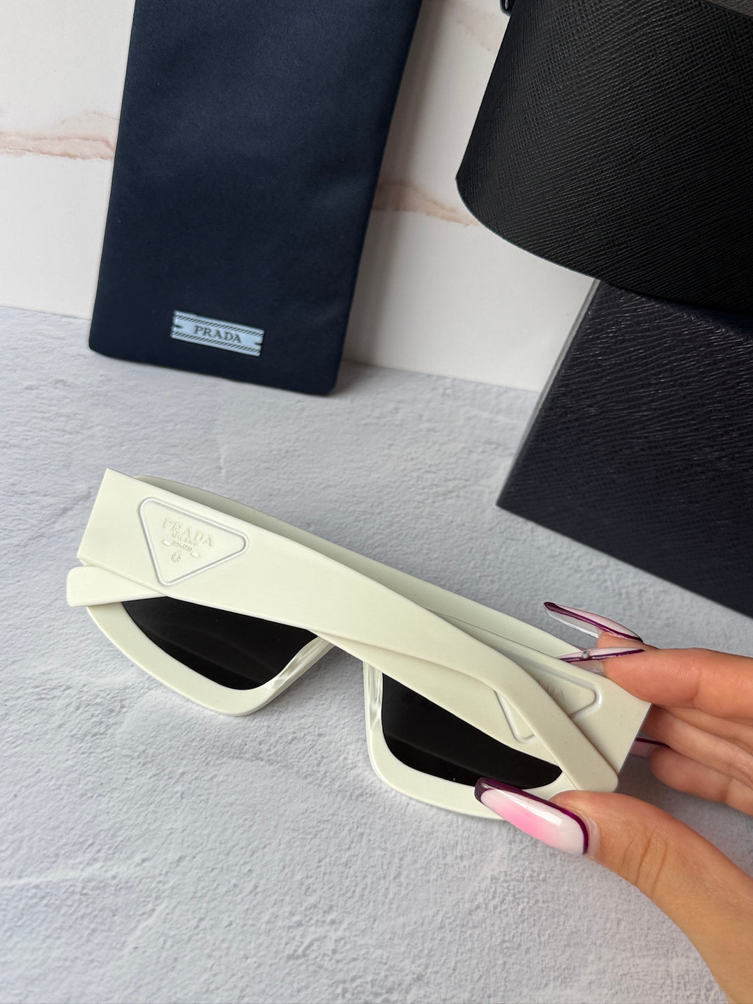 White mask-style sunglasses with black lenses, side profile held in hand
