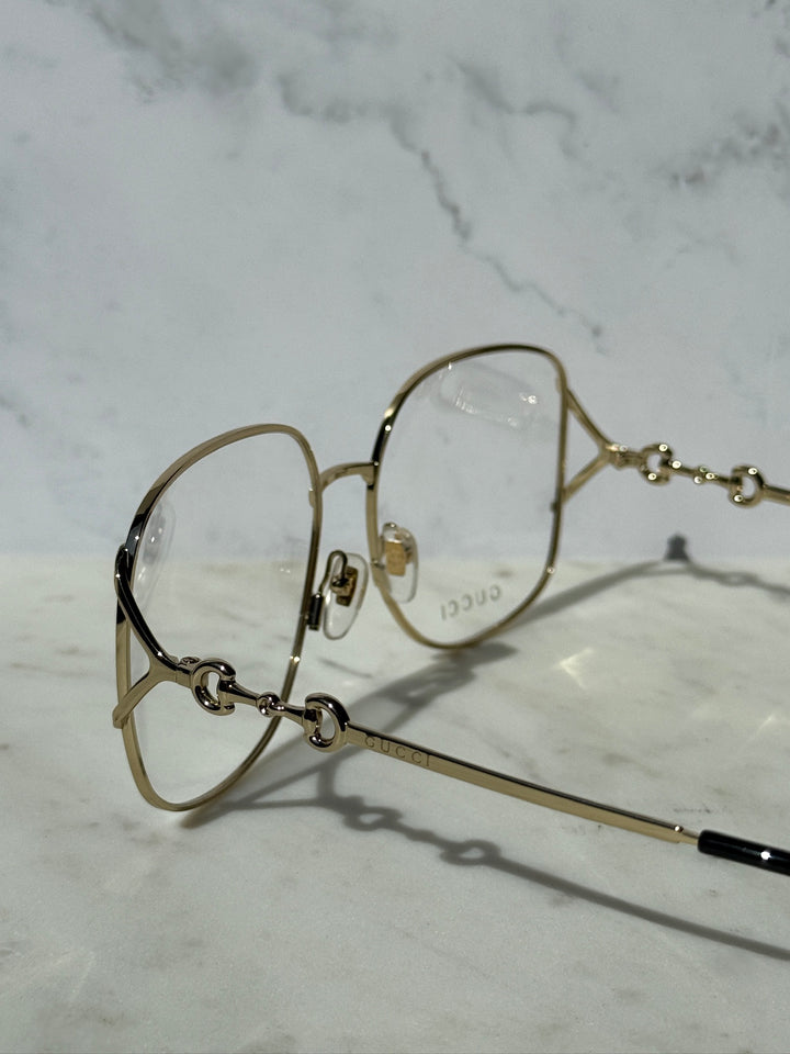 Gold oversized eyeglass frames with horsebit detail and clear lenses