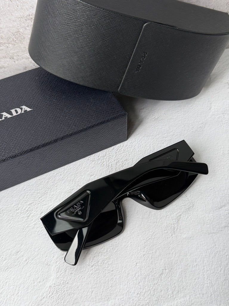 Black PRADA sunglasses with dark lenses, close-up with case and temple