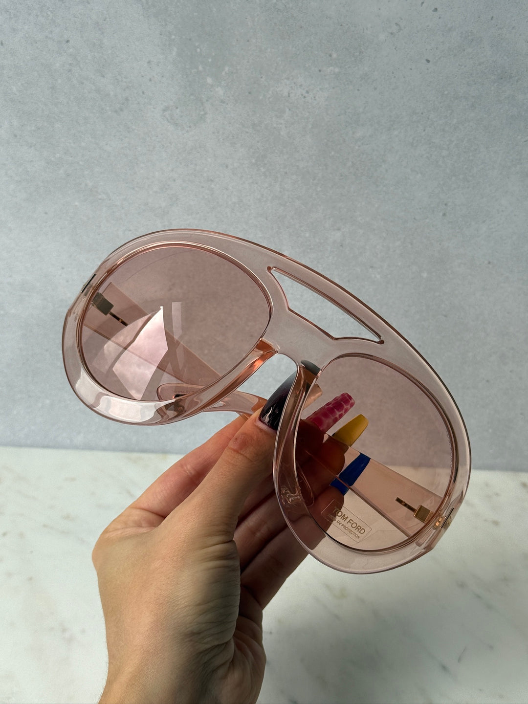Pink oversized mask sunglasses shown from above with tinted lenses and gold accents