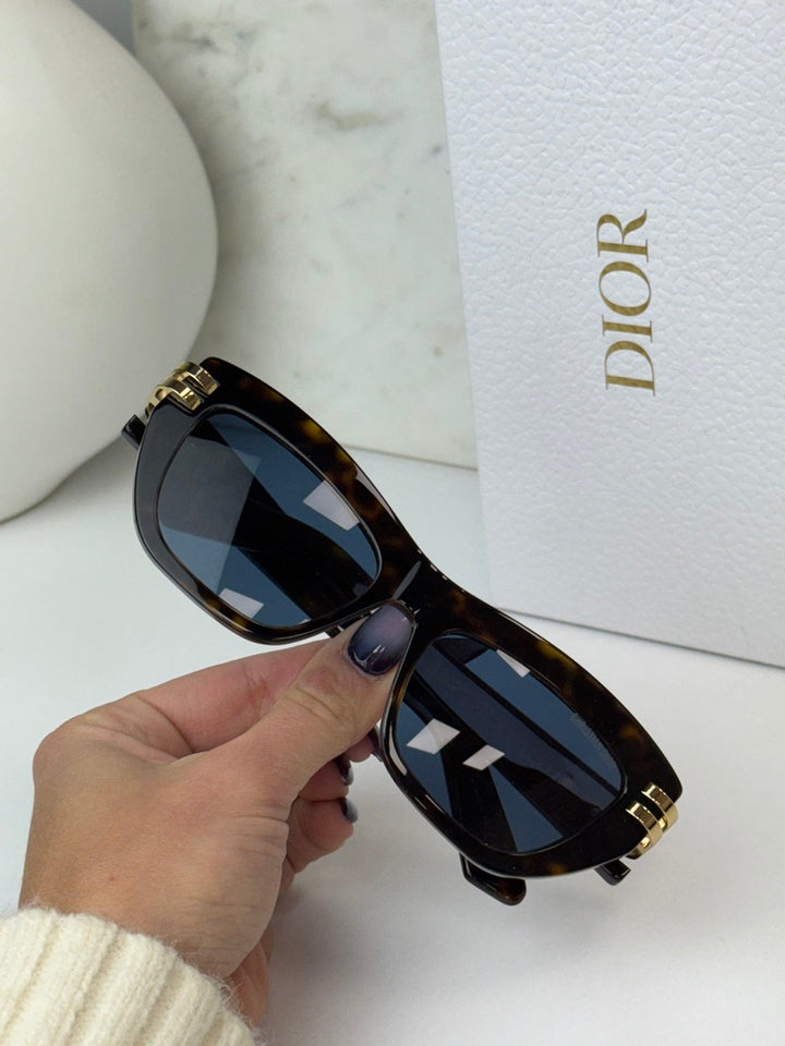 Havana brown Dior sunglasses detail with blue lenses, gold hinge accents, and Dior branding