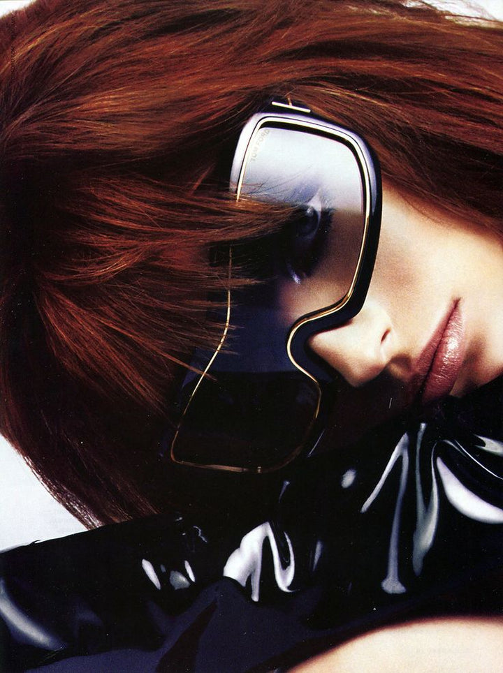 Oversized mask sunglasses on model: black frame, gold accents, purple-tinted lenses