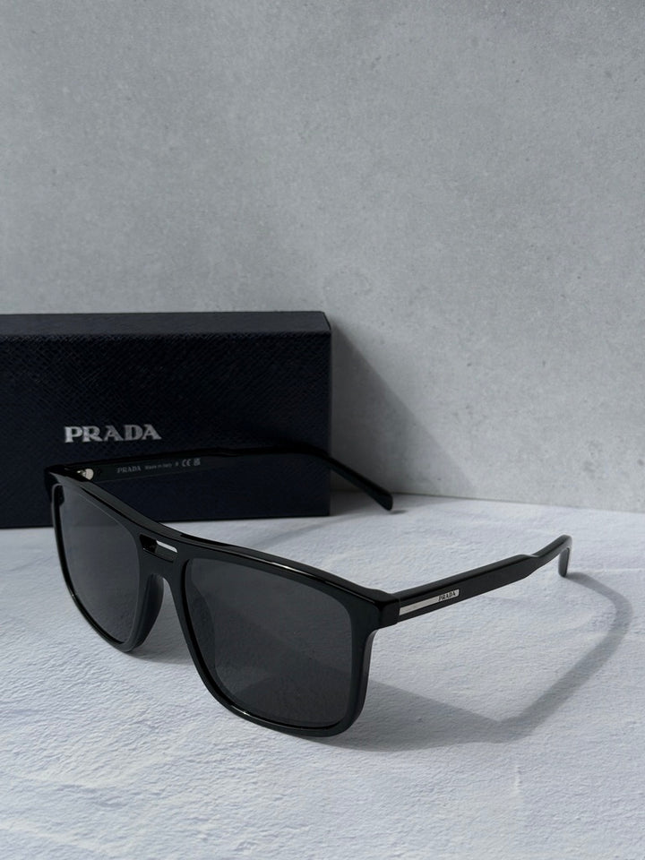 Black aviator sunglasses with angular frame and dark lenses, PRADA branding
