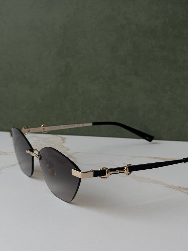 Gucci angled cat-eye sunglasses with gold frame, dark lenses, and horsebit bridge
