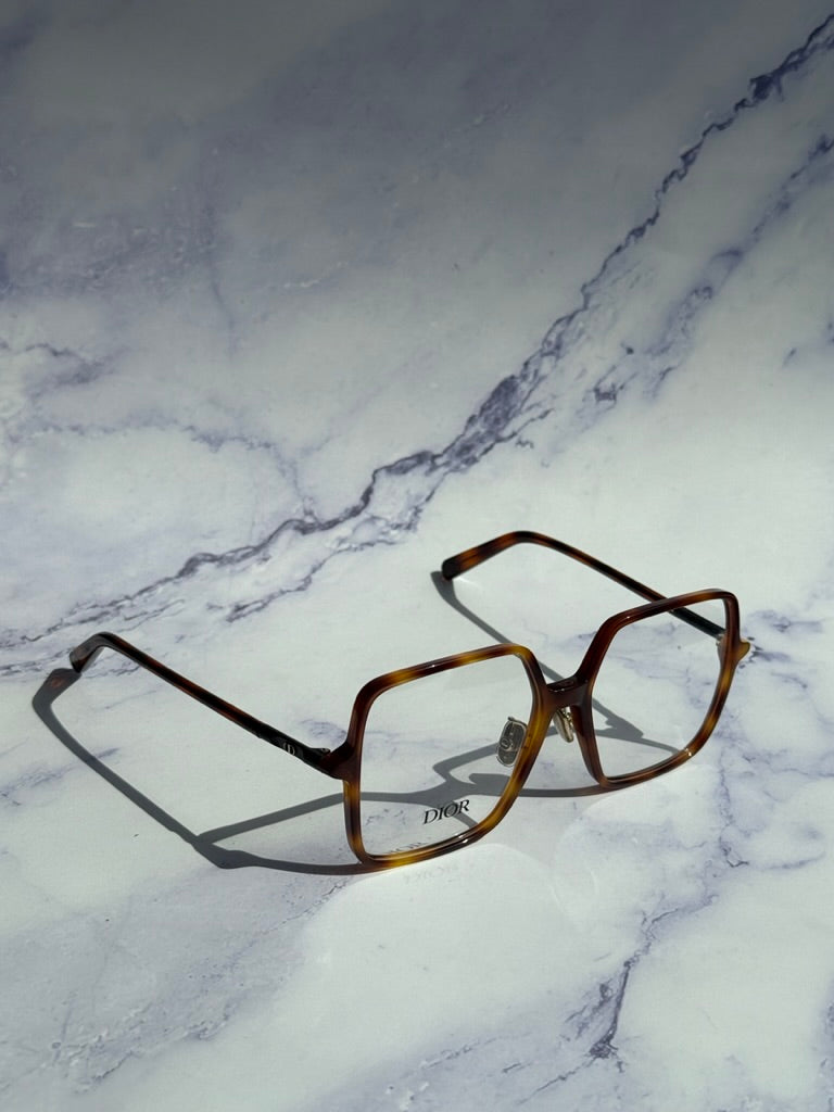 Havana brown square eyeglasses with clear lenses, angled view on surface