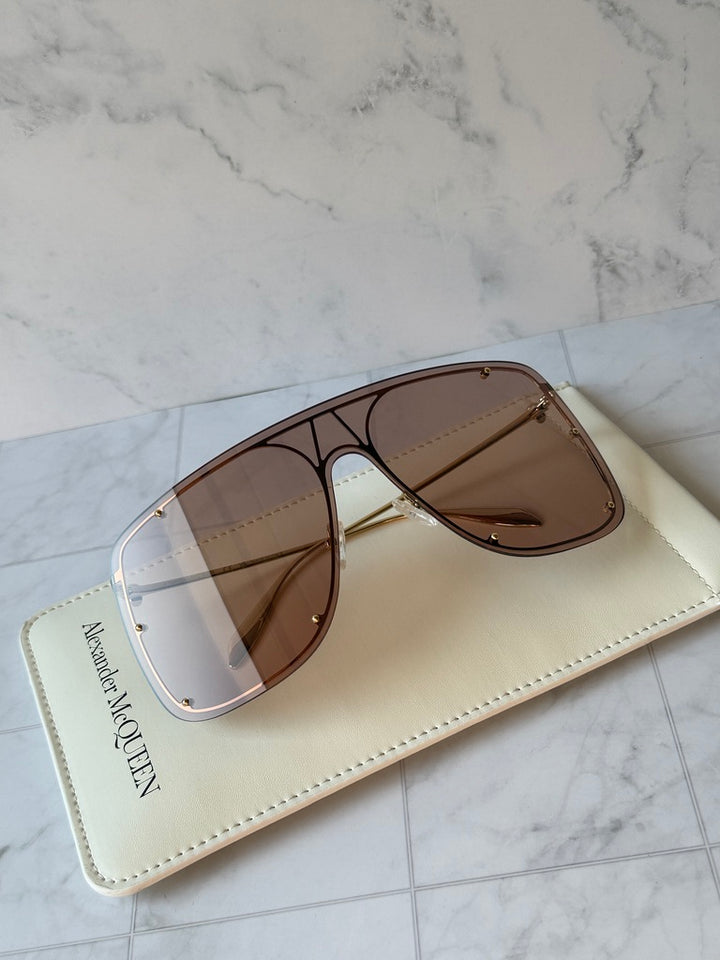 Oversized shield sunglasses with nude frame and brown tinted lenses, gold hinges