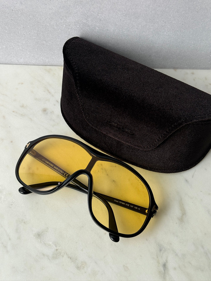 Black sunglasses with yellow lenses, placed on a black fabric case