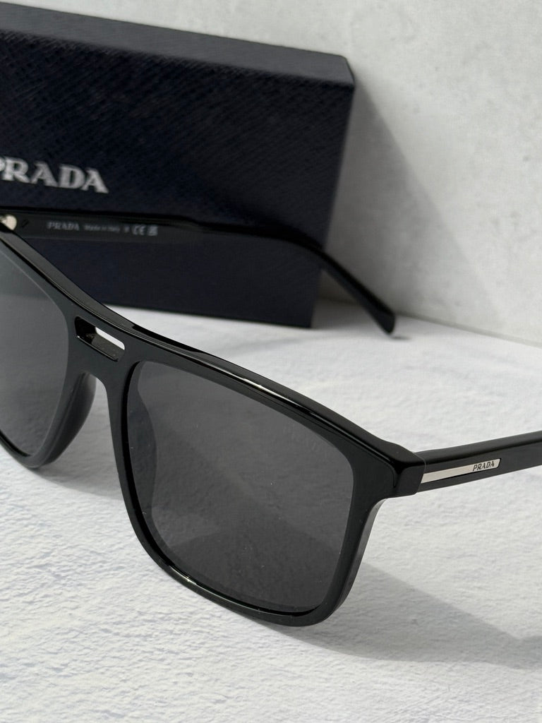 Close-up of black aviator sunglasses frame with dark lens and PRADA temple detail
