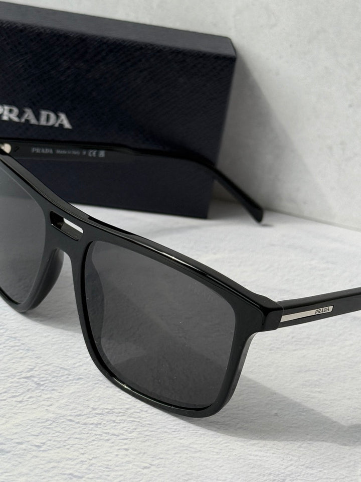 Close-up of black aviator sunglasses frame with dark lens and PRADA temple detail