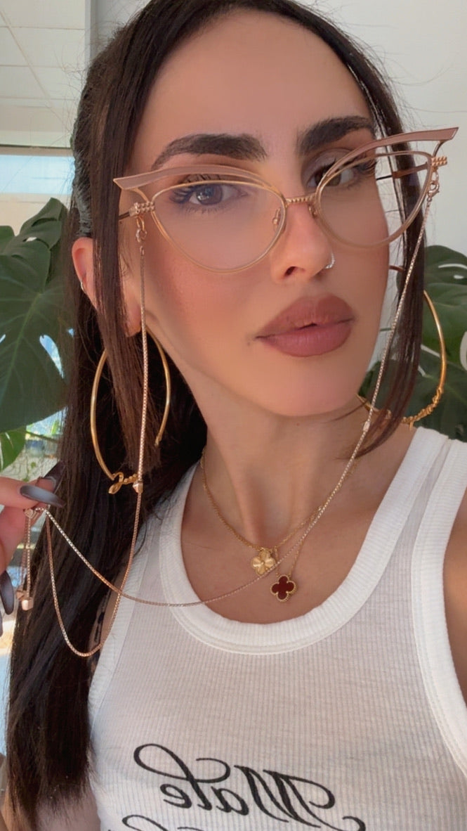 Cat-eye eyeglass frames on a model, with gold-tone metal and beige lenses