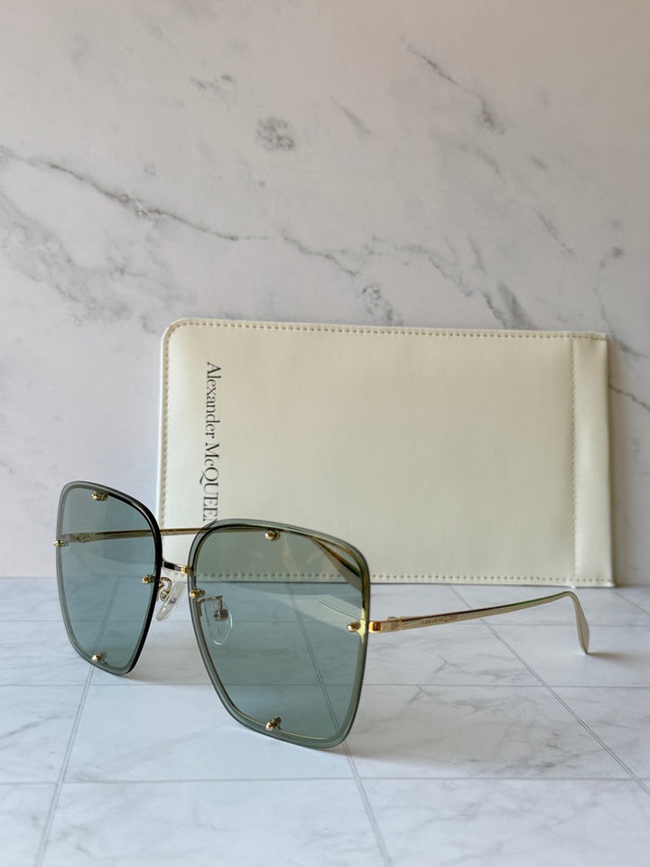 Oversized square sunglasses with green lenses and slim gold side arms