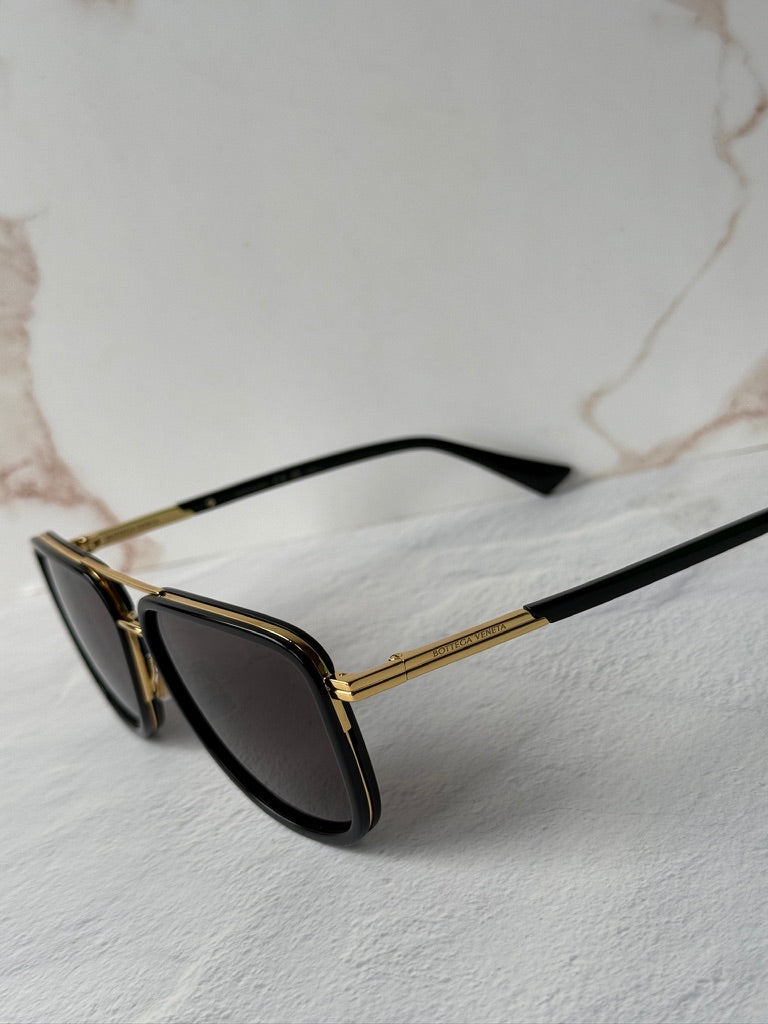 Black squared aviator sunglasses, side view, dark lenses with gold-tone frame detail