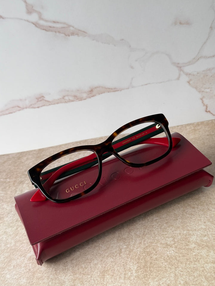 Square dark tortoise eyeglass frames with red temples and green stripe detail
