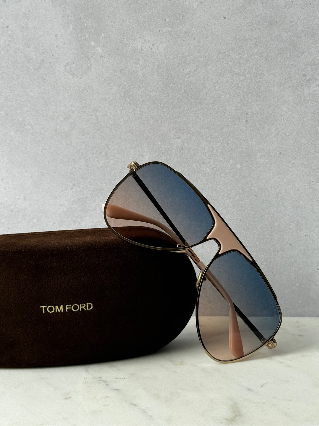 Tom Ford aviator sunglasses with blue gradient lenses and gold metal frame in brown case
