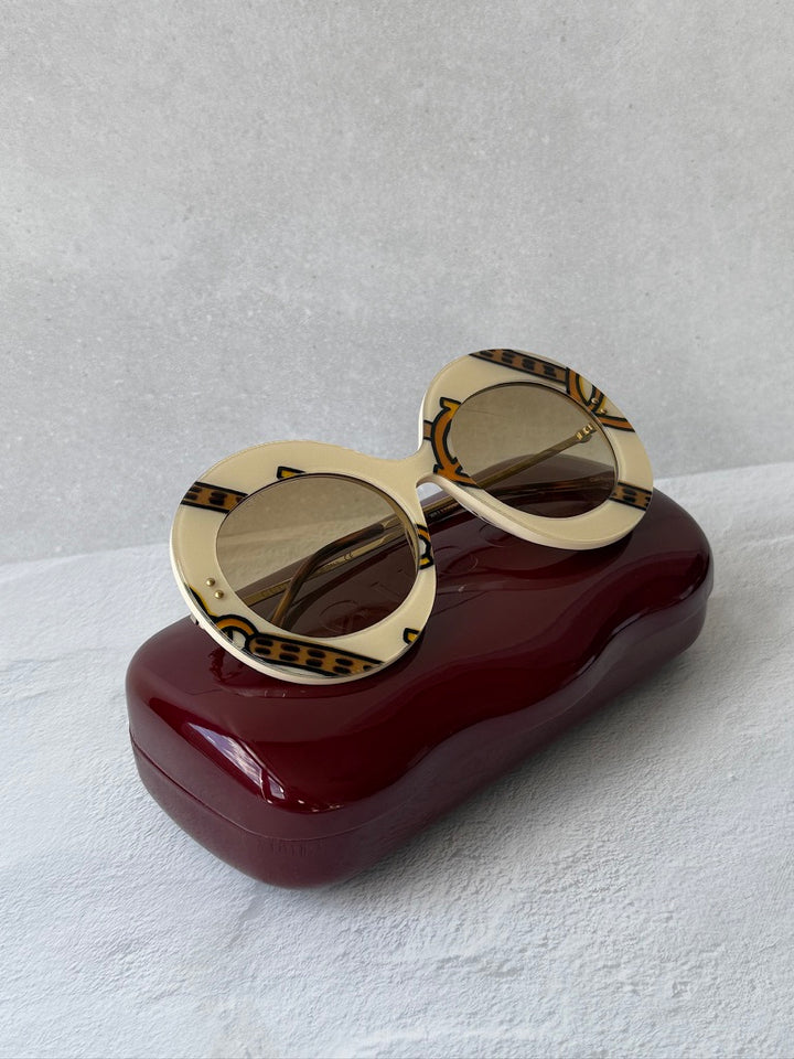 Round sunglasses with cream frames, brown lenses, patterned GG temples.