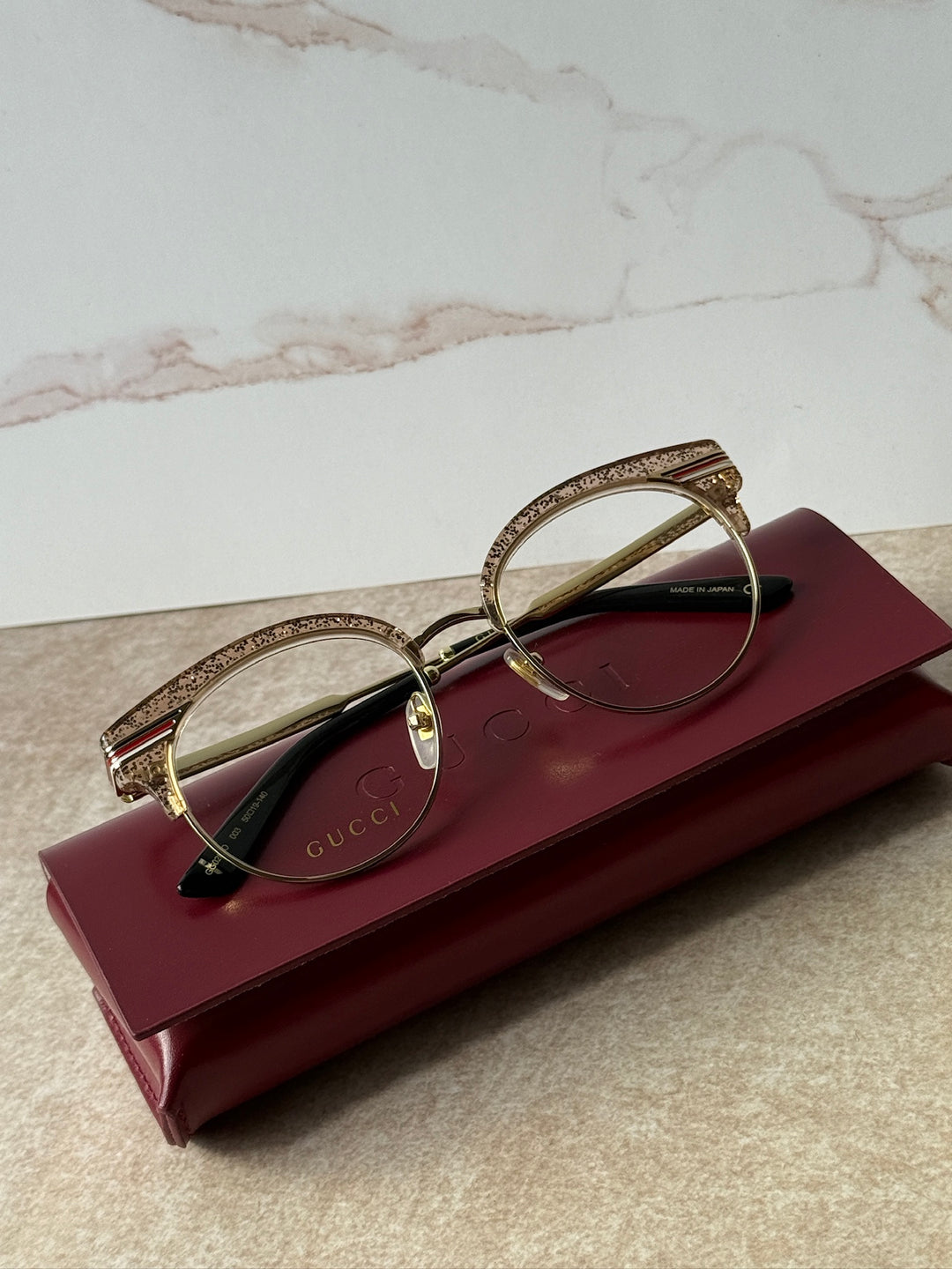 Pink glitter cat-eye eyeglass frames with gold-tone rims and dark lenses