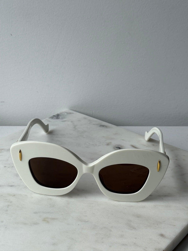 White cat-eye sunglasses with dark oval lenses and gold accents, front view
