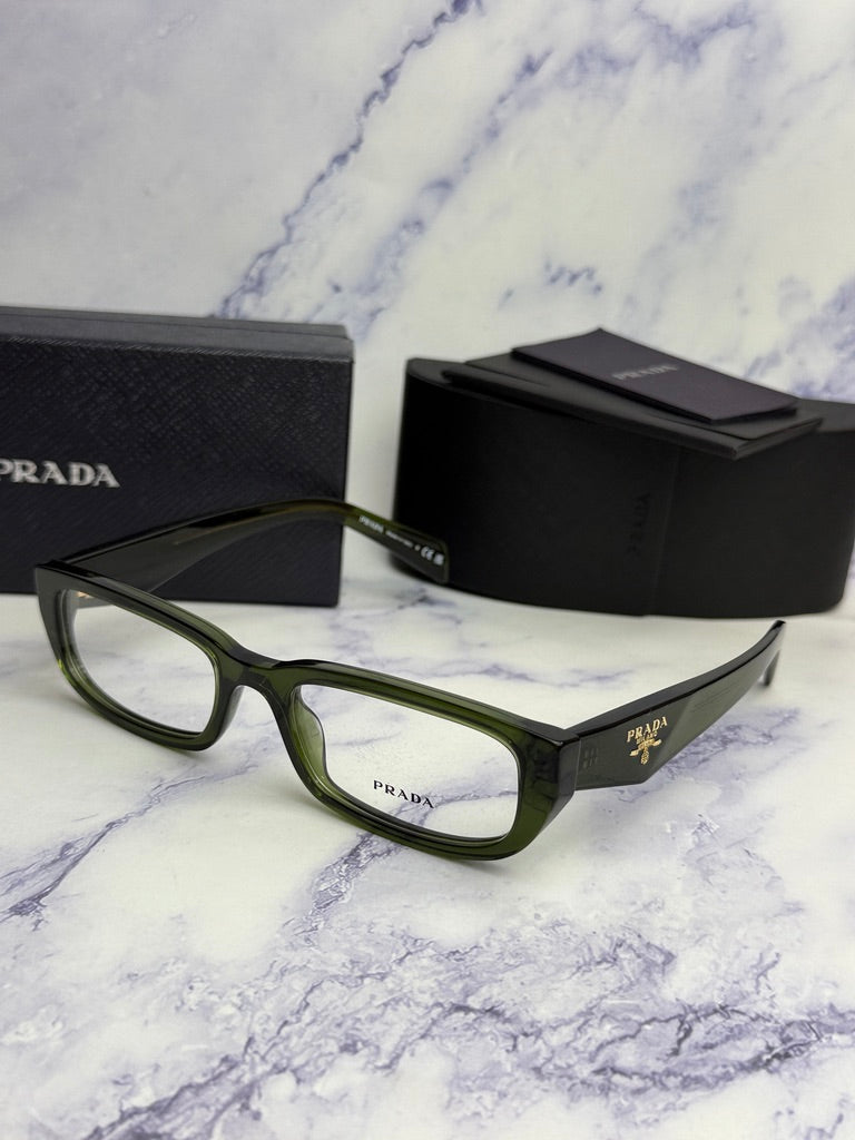 Transparent green eyeglass frames angled on surface with black Prada case beside.
