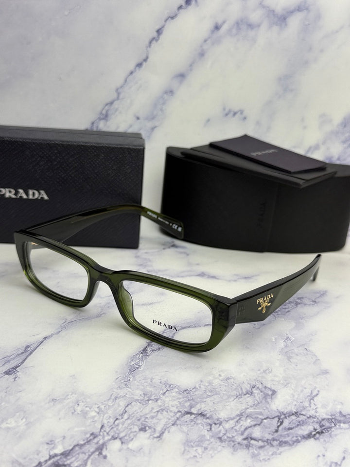 Transparent green eyeglass frames angled on surface with black Prada case beside.