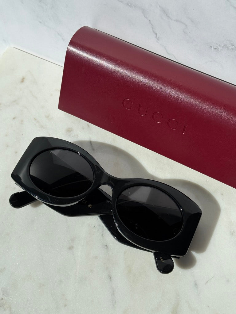 Black rectangular sunglasses with thick frames, dark lenses, and side logo