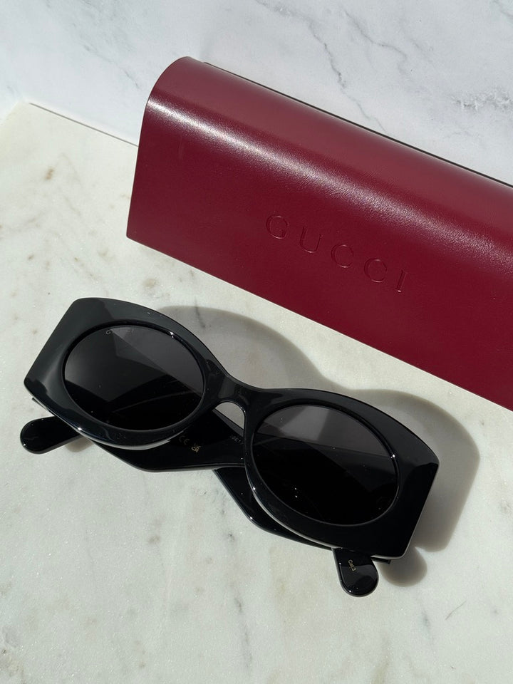 Black rectangular sunglasses with thick frames, dark lenses, and side logo