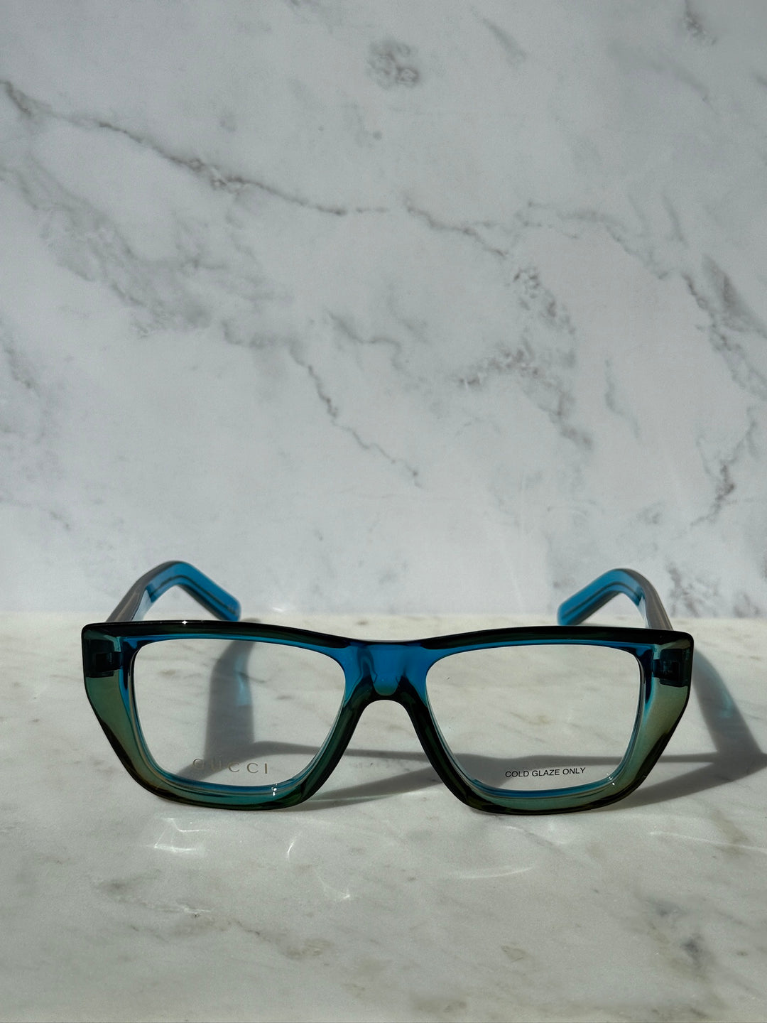 Blue Gucci eyeglasses frames with rectangular clear lenses and teal temples.