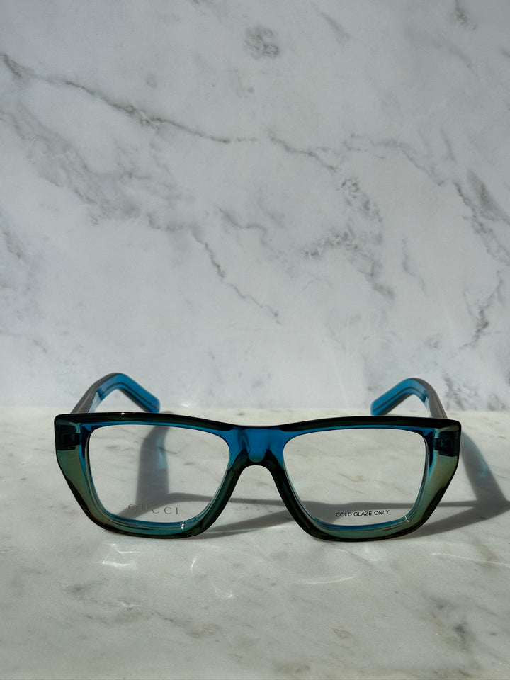 Blue Gucci eyeglasses frames with rectangular clear lenses and teal temples.