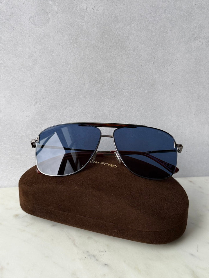 Blue mirrored aviator sunglasses with metal frame, on brown protective case
