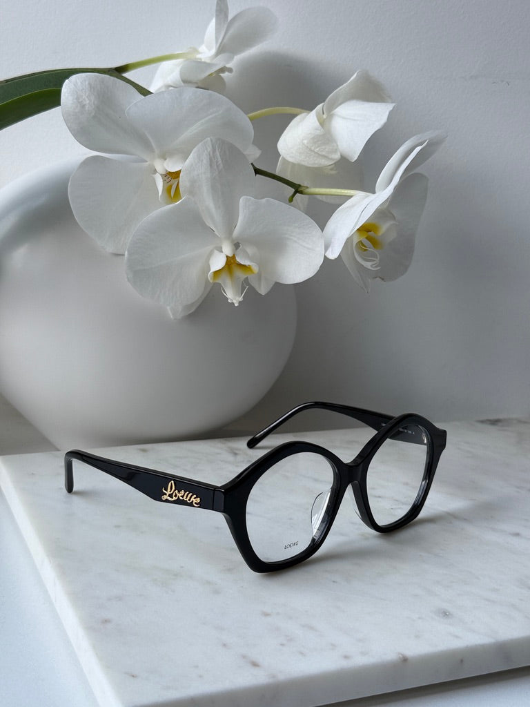 Black curvy eyeglass frames, front view with gold Loewe logo on temple arm
