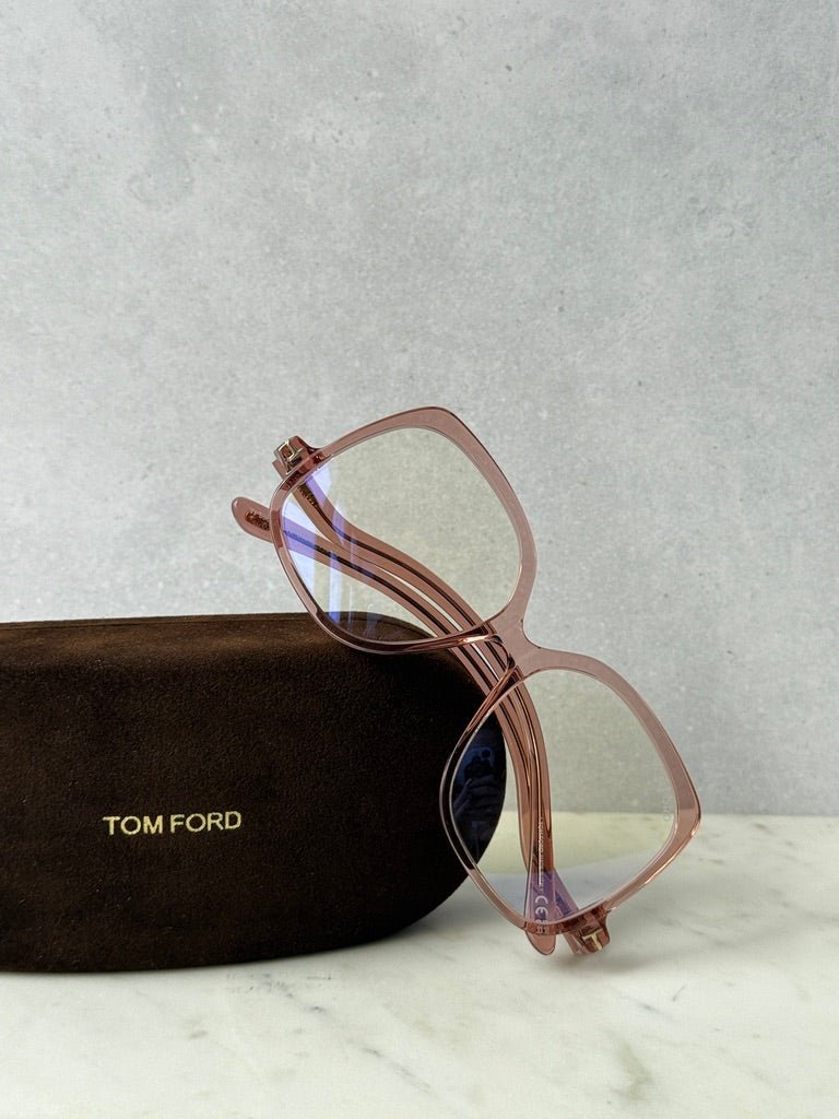Pink oversized blue-light glasses frames with transparent lenses, angled on case