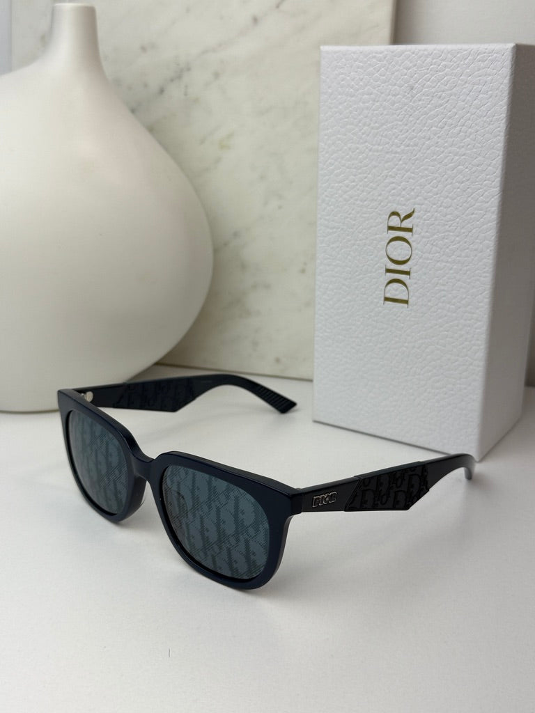 Navy Dior sunglasses with dark mirror lenses and branded temple, resting on display.