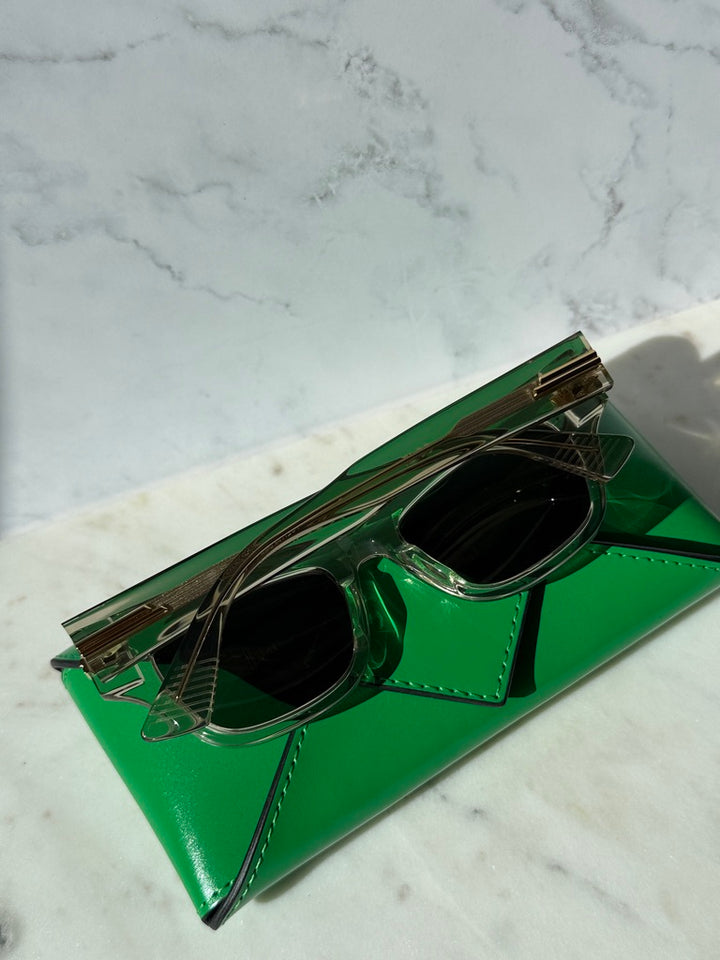 Mitre rectangular sunglasses, angled view, clear frame with gold accents and dark lenses