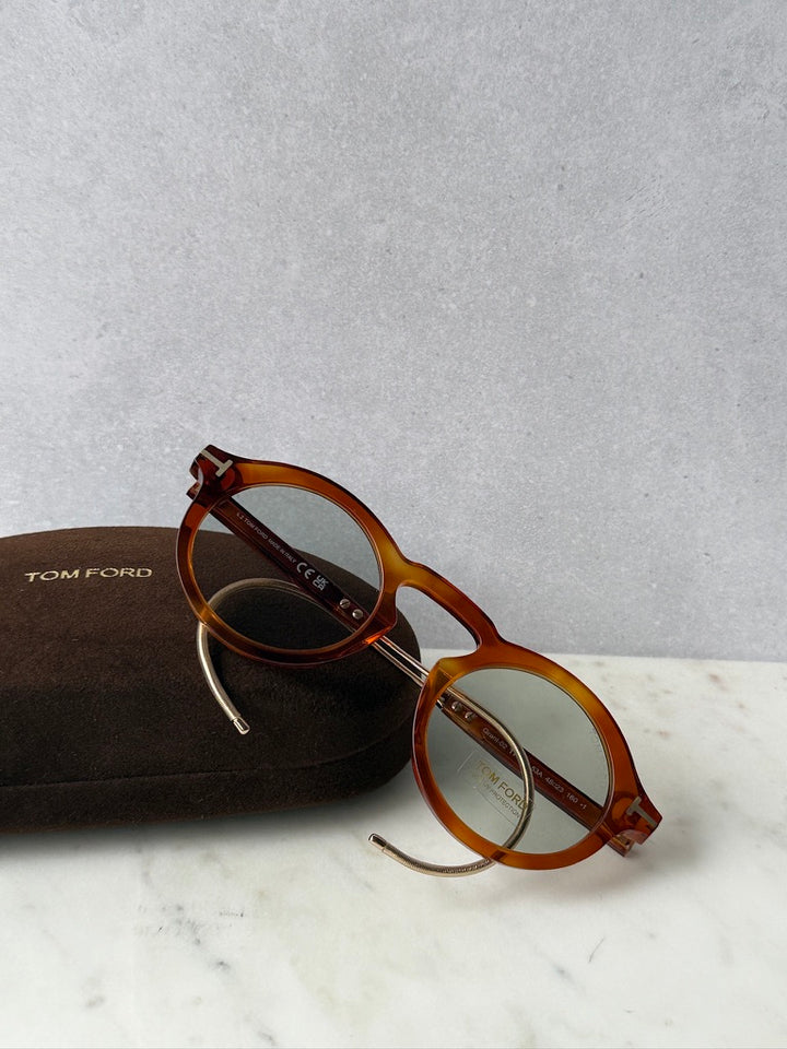 Brown round sunglasses with gold-tone temples, shown with a brown protective case